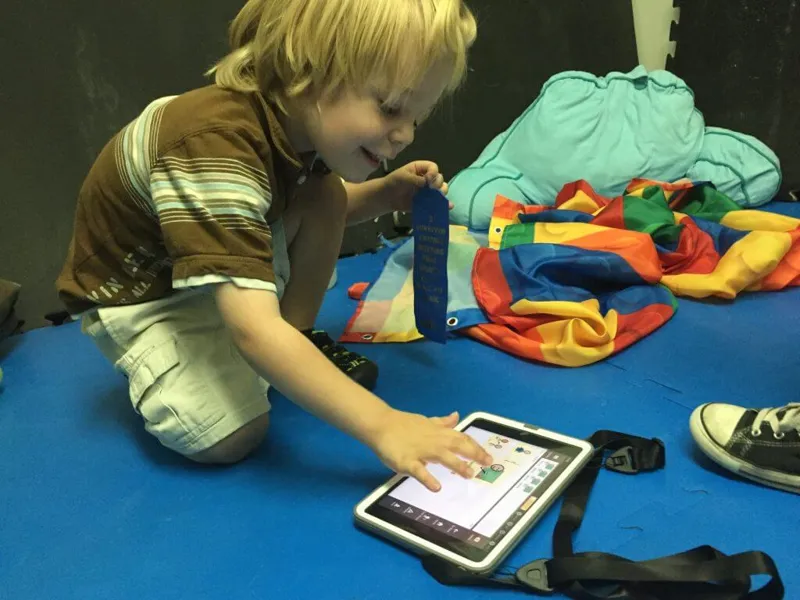 A young boy tapping picture symbols on Avaz on a tablet